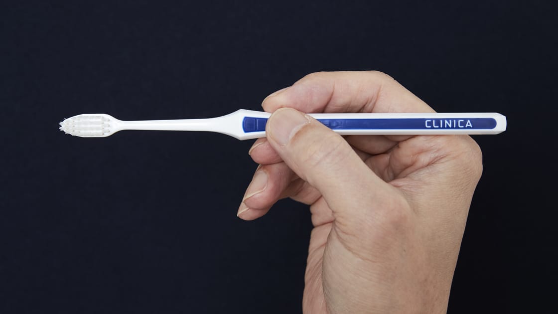 歯ブラシを鉛筆のように持つ手元